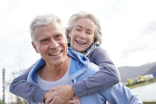  Fun loving senior couple piggyback riding outdoors