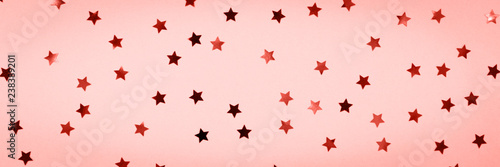 Golden star sprinkles on pink. Festive holiday background. Celebration concept . Living coral theme - color of the year 2019