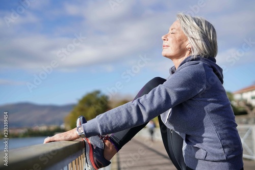  Flexible senior woman stretching outdoors after jog