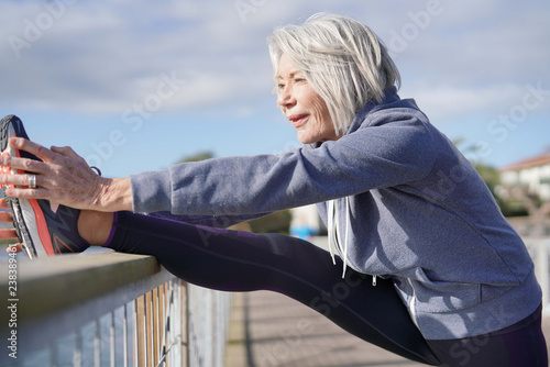 Tableau sur toile Flexible senior woman stretching outdoors after jog