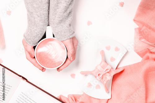 Female hands holding cup of cappuccino. Gift alike dessert with heart shape sprinkles. Flat lay. Valentines concept. . Living coral theme - color of the year 2019