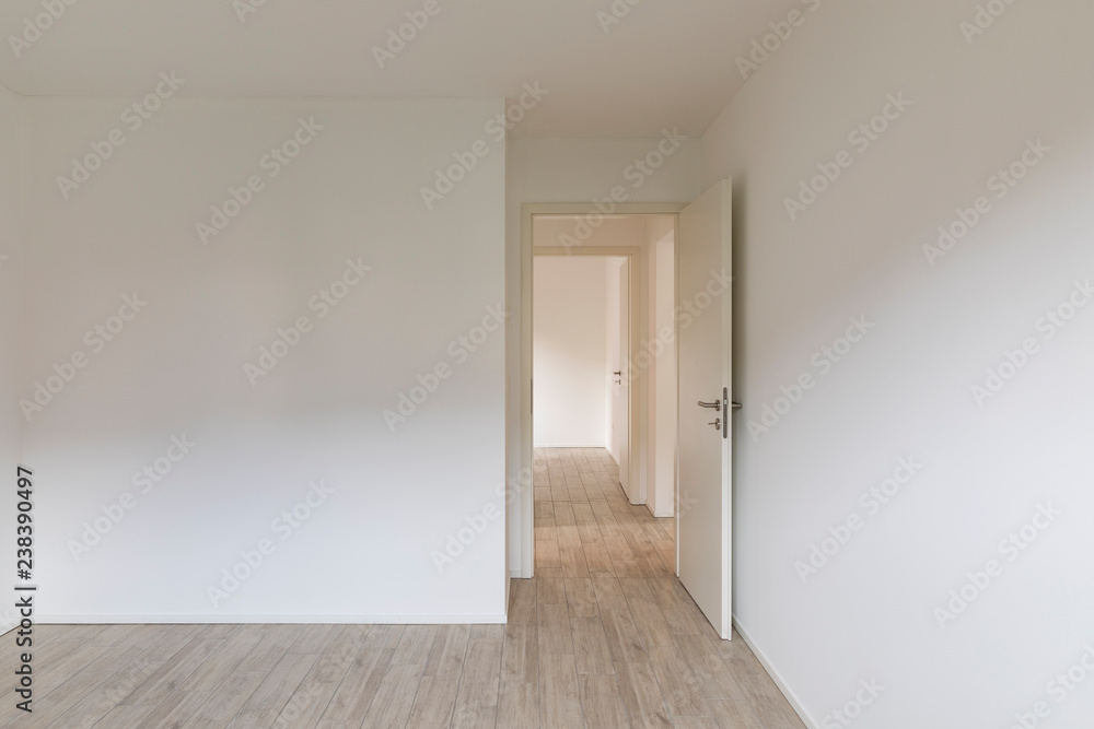 Empty room with white walls and open door on the right Empty room with white walls and open door on the right