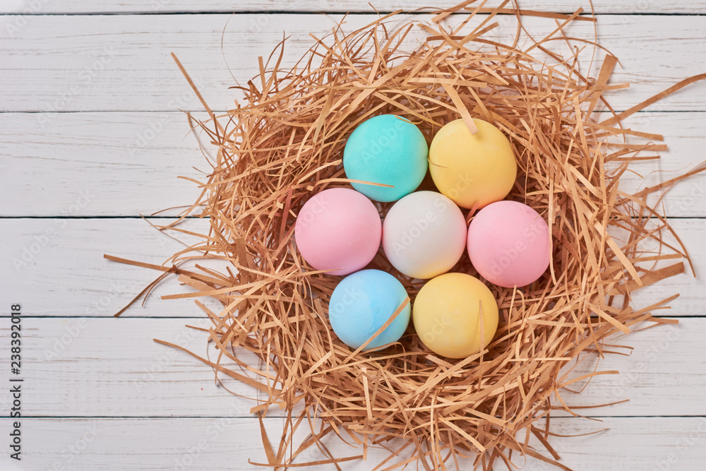 Colorful easter eggs in paper nest on a white background, top view. Easter decorations Colorful easter eggs in paper nest on a white background, top view. Easter decorations