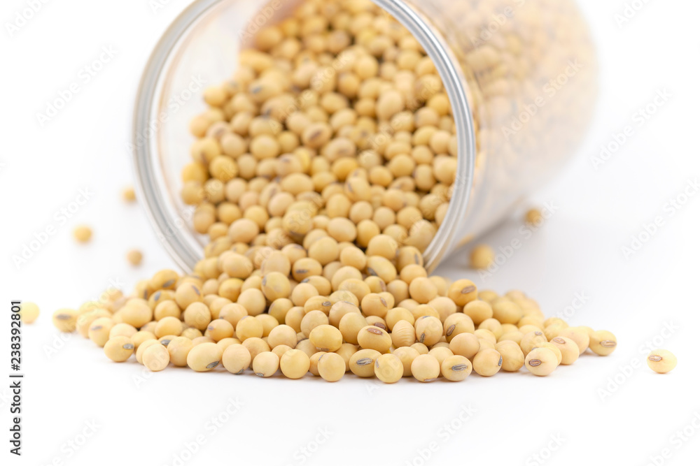 Soybeans is poured out of a glass jar and spread at on white background. Soybeans is poured out of a glass jar and spread at on white background.