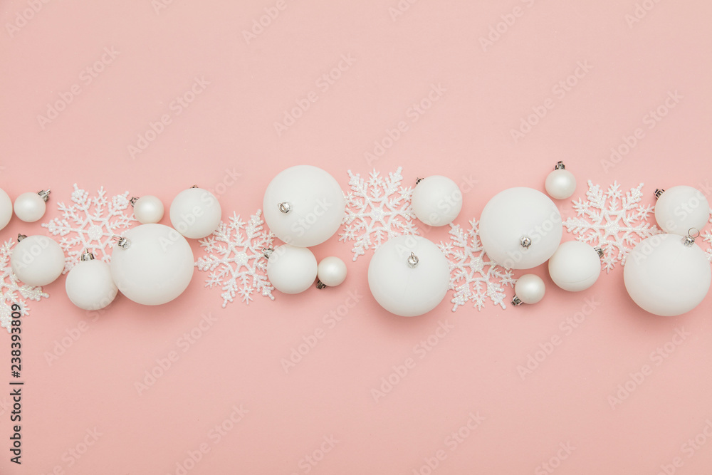 Festive winter composition. White christmas balls and snowflakes on a pastel pink background
