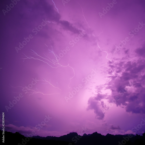 Lightning bolt striking at night with purple cloudy sky