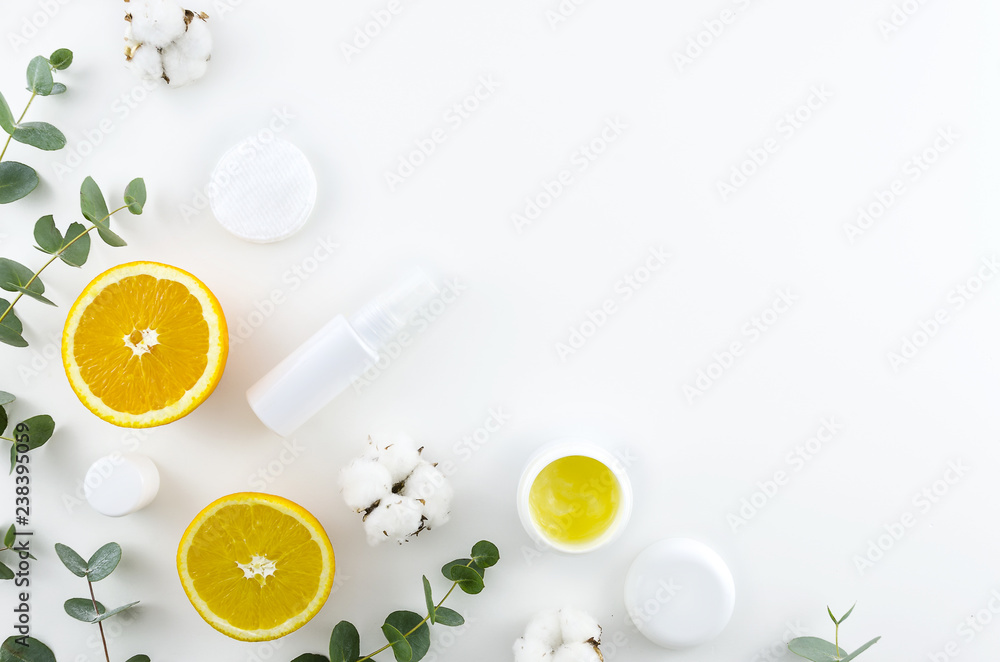 Flat lay home made cosmetics concept. Corner frame with green eucalyptus ,oranges, cotton flowers and cosmetic jars. Top view mockup. Minimal natural eco friendly design