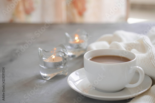 Cup of cocoa on a table, candles and knited blanket.