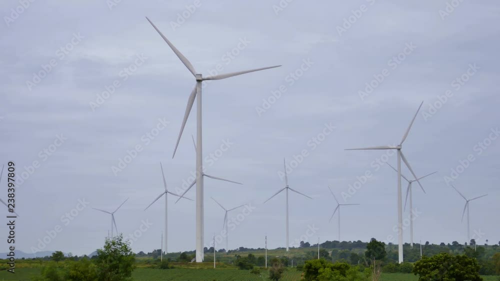 Wind turbines in the green field are rotating with overcast Wind turbines in the green field are rotating with overcast