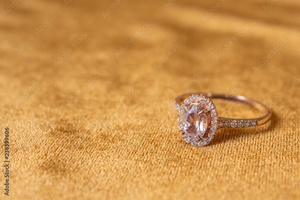 Jewelry pink diamond ring on golden fabric background close up Jewelry pink diamond ring on golden fabric background close up