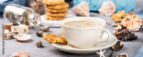 Cup of coffee and biscuits with seashells and decorations. Dreams of sea vacation and concept. Banner.