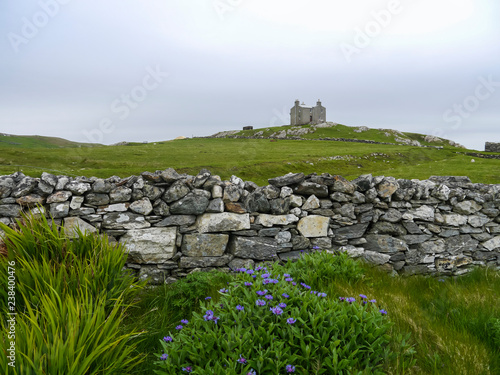 old drystone wall with abandoned house on a hill