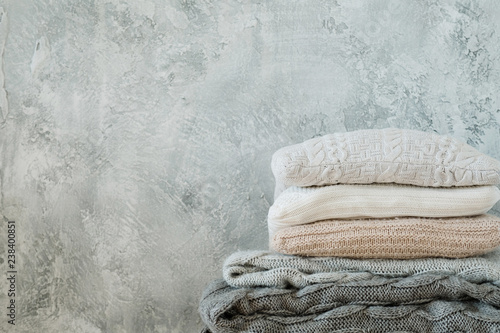 фотографія pile of knitted throw blankets and plaids on shabby gray background