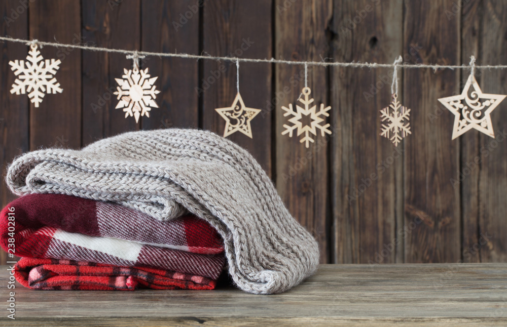 stack of plaids and Christmas decorations on wooden background - obrazy, fototapety, plakaty 