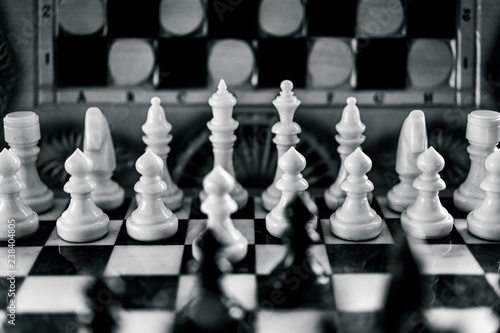 White chess figures defend against black figures on chessboard