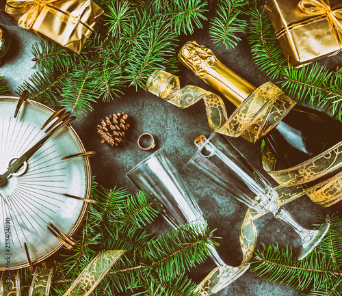 New Year Eve tradition rutual put gold ring to champagne. Spanish and Latin American New year traditions. Two champagne grasses, bottle of champagne, vintage clock and Christmas decorations. Top view photo