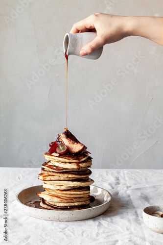 Woman pouring caramel syrup on pancakes stack photo