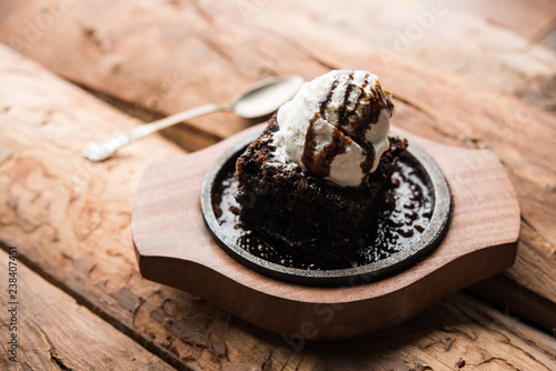 sizzling chocolate brownie is a sweet dish made using scoop of ice-cream on top served with a generous pouring of melted chocolate. server hot. selective focus photo