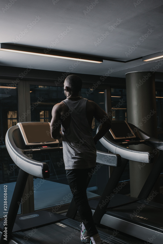 Black man running on treadmill in gym Black man running on treadmill in gym