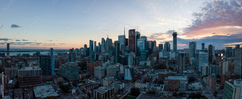 Aerial panoramic view of a modern cityscape of Downtown Toronto, Ontario, Canada, during a vibrant sunset.