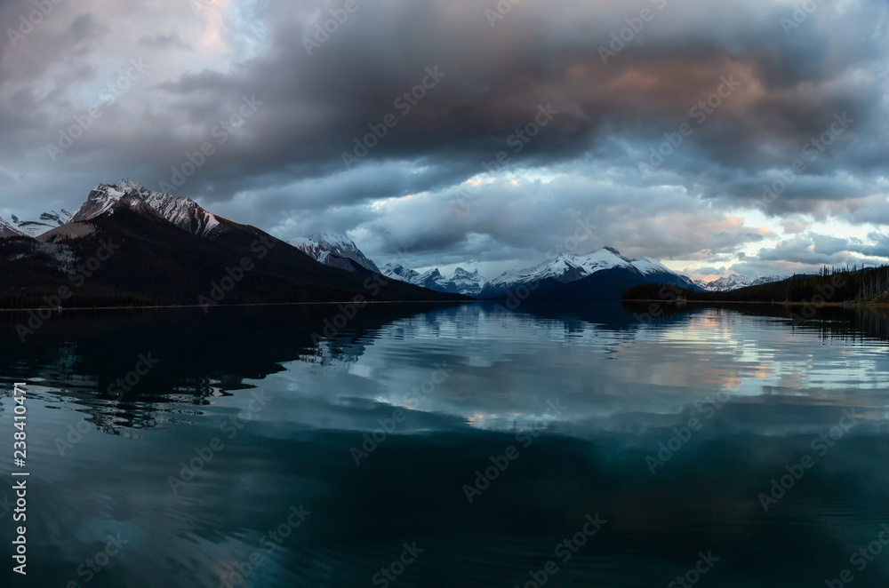 Panoramic Landscape View of a Glacier Lake during a Dramatic Cloudy Sunset. Taken in Maligne Lake, Jasper National Park, Alberta, Canada.