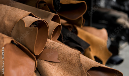 Different pieces of leather in a rolls. The pieces of the colored leathers. Rolls of natural brown red leather. Raw materials for manufacture of bags, shoes, clothing and accessories. photo