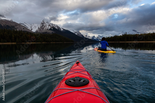 Kayaking in a peaceful and calm glacier lake during a vibrant cloudy sunset. Taken in Maligne Lake, Jasper National Park, Alberta, Canada. © edb3_16