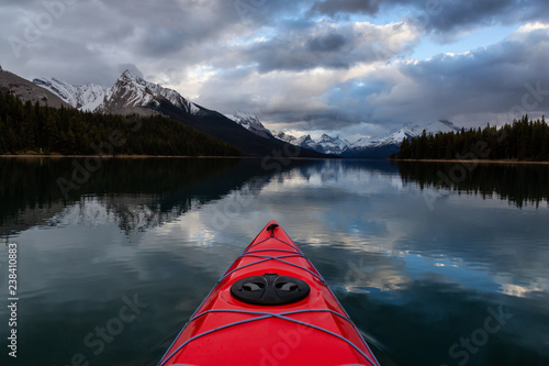 Kayaking in a peaceful and calm glacier lake during a vibrant cloudy sunset. Taken in Maligne Lake, Jasper National Park, Alberta, Canada. © edb3_16