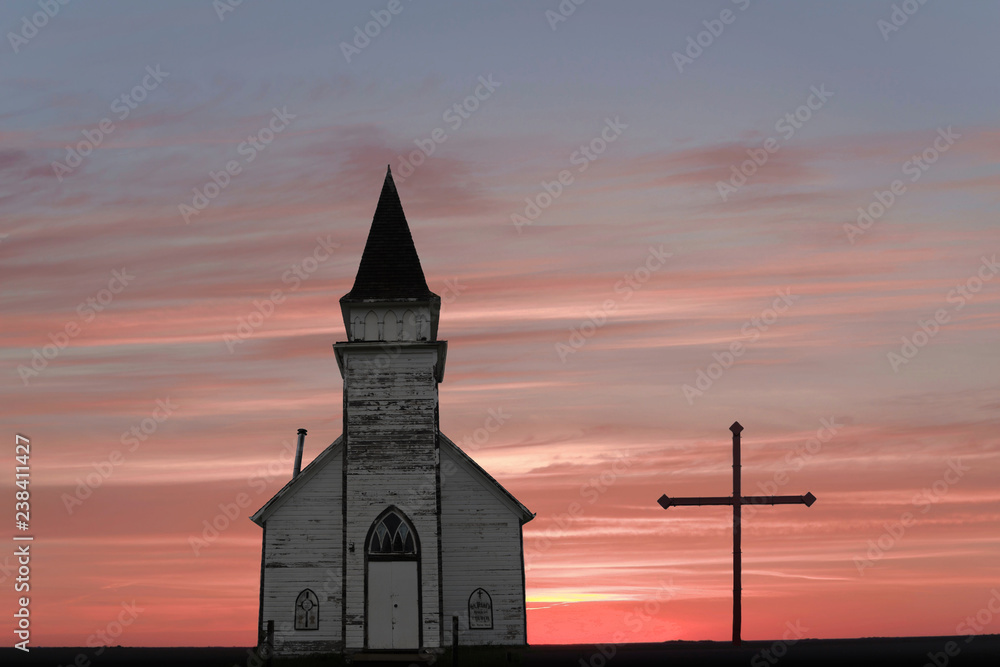 country church and a cross against a prairie sunset