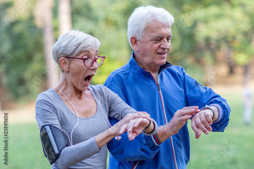 mature couple looking at distance tracker watch after jogging in the park