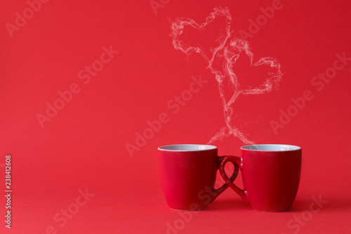 Cups of tea or coffee with steam in two heart shape on red background. Valentine's day celebration or love concept. Copy space