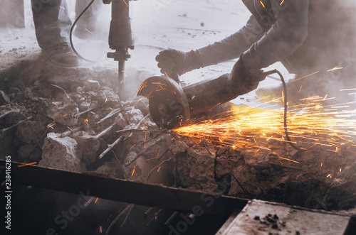 Cutting metal reinforcement in reinforced concrete. Sparks from friction with metal. Disassembly work. Circular electric saw.