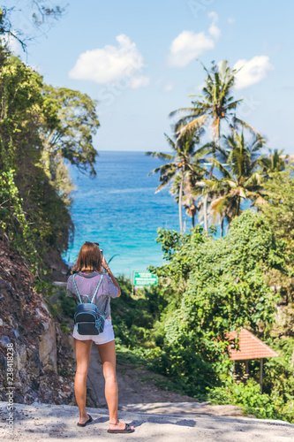 Young woman tourist taking photo of beautiful tropical landscape on her smartphone. Bali island. © belart84