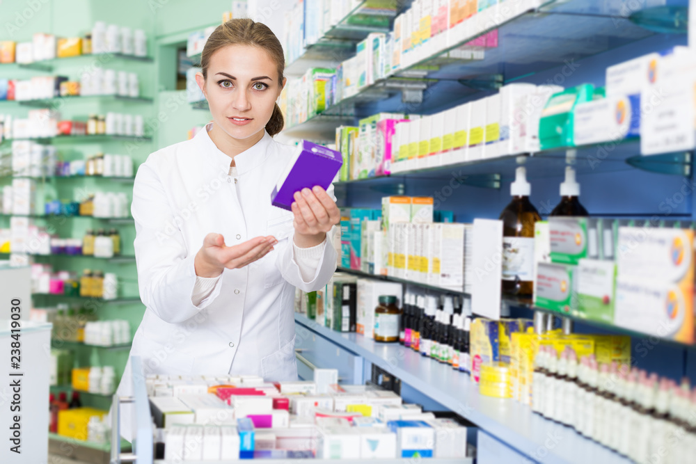 Portrait of positive female pharmacist is sshowing medicines