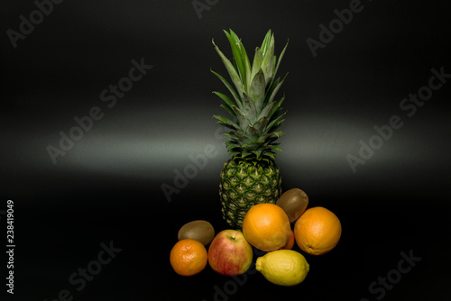 Pineapple orange mandarin kiwi apple with black background