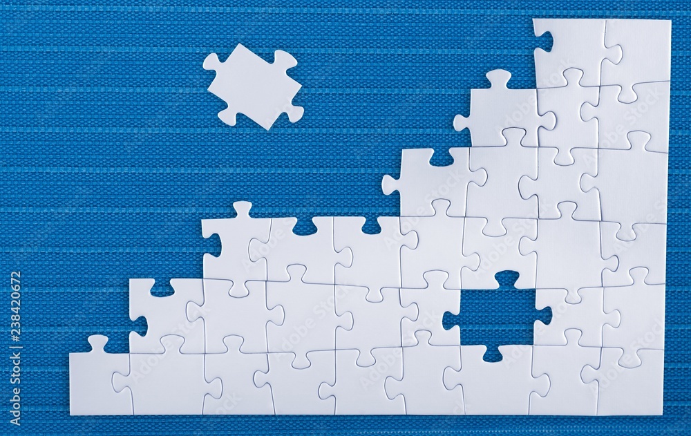 Fototapeta premium Fitting last puzzle piece on blue background