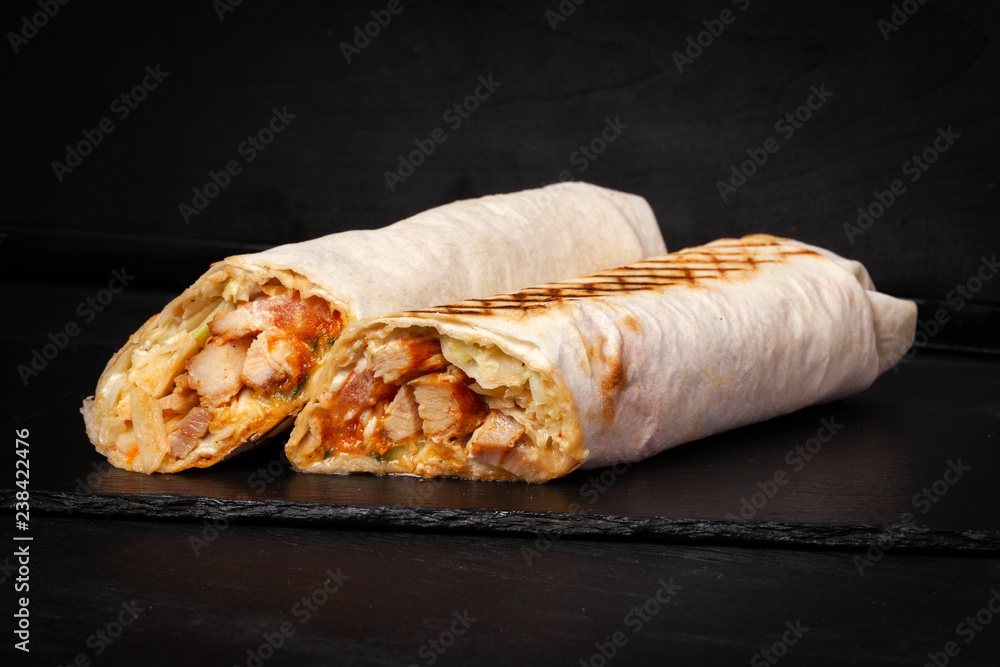 Shawarma sandwich gyro- fresh roll of thin lavash (pita bread) filled with  grilled meat, mushrooms, cheese, cabbage, carrots, sauce, green.  Traditional Eastern snack. On dark black background Stock Photo | Adobe  Stock