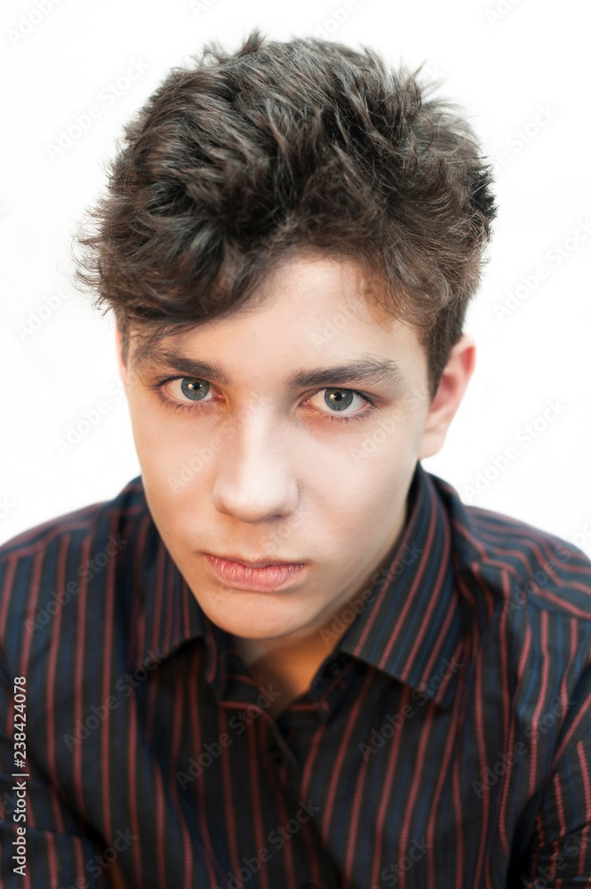 Vertical portrait of an angry teenager in a dark shirt on a light background Vertical portrait of an angry teenager in a dark shirt on a light background