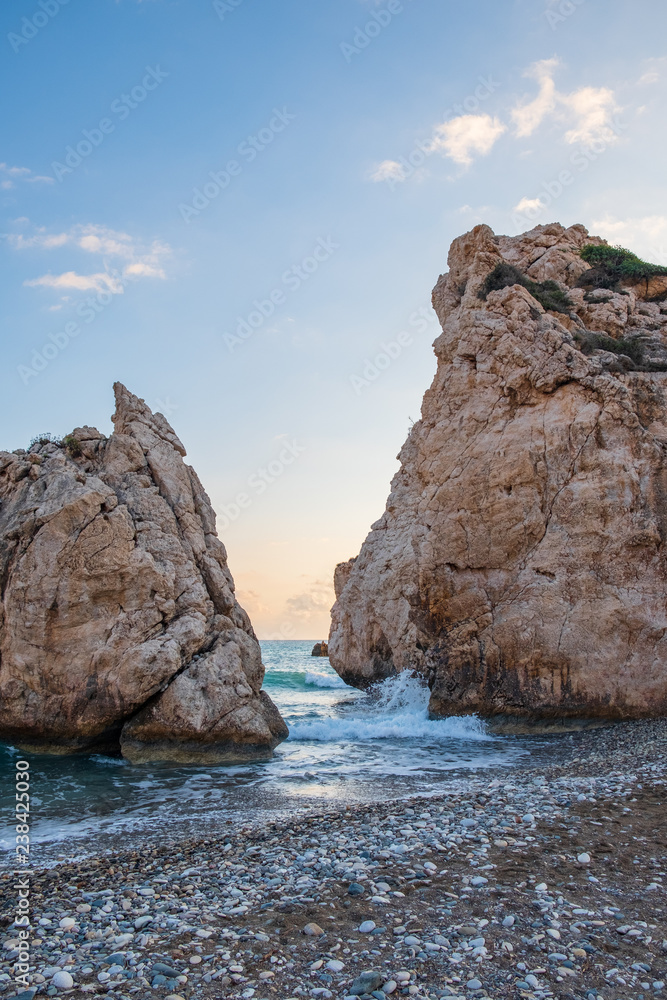 Naklejka premium Afternoon view of breaking waves at the pebbly beach around Petra tou Romiou, also known as Aphrodite's birthplace, in Paphos, Cyprus.