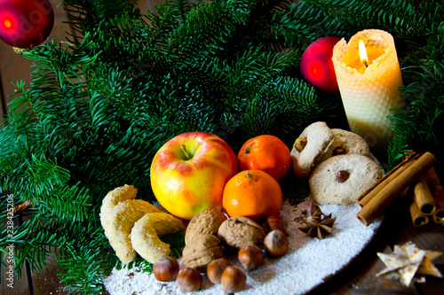 traditional german christmas sweets plate with fruits, nuts aqnd cookies, decorated with spices, fir branches and paper stars photo