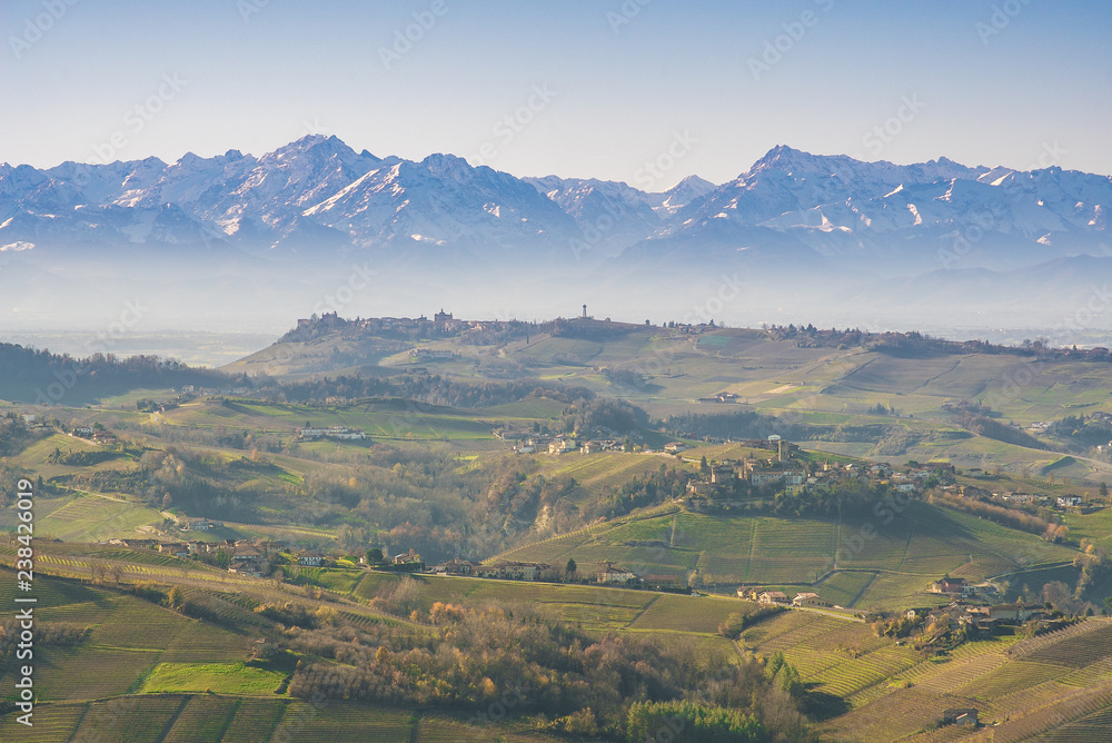 Autumnal hills and vineyards in Langhe Monferrato region with mountains on background in Piedmont, Northern Italy.