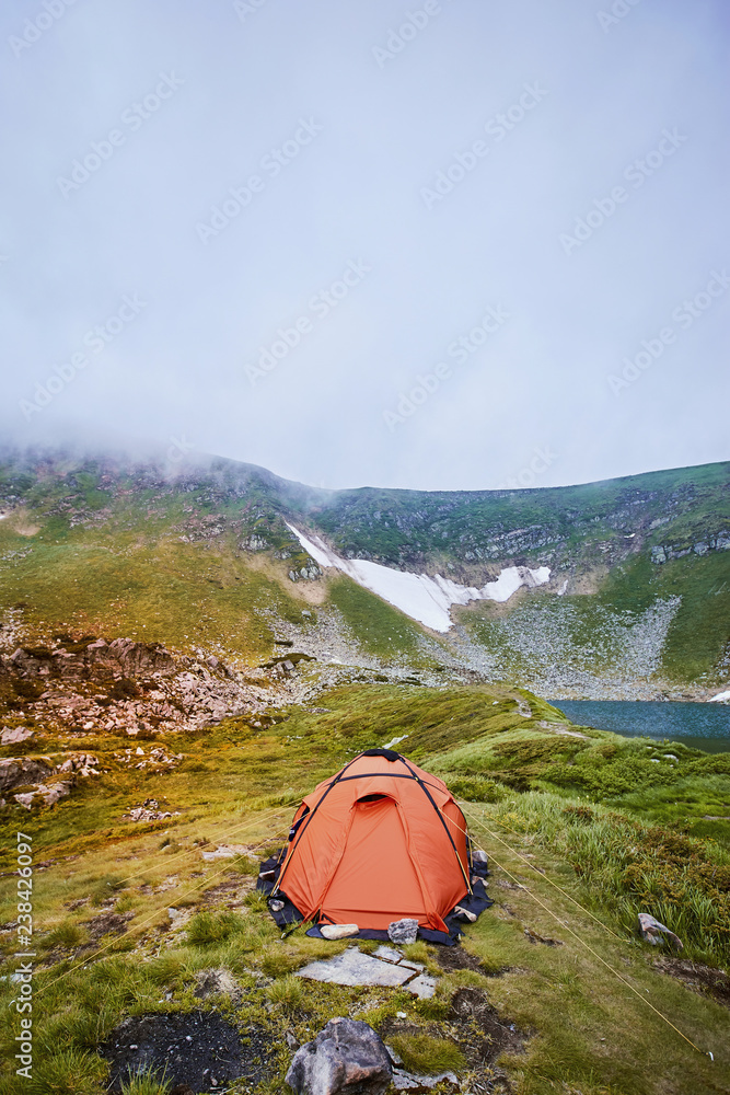 Camping with a tent near a mountain lake in the mountains.