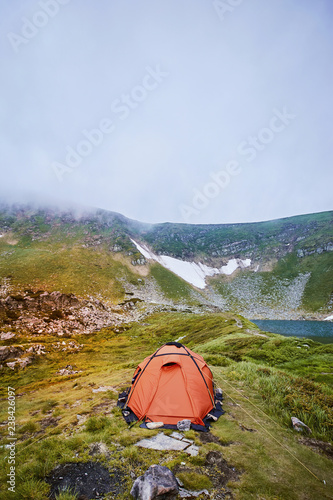 Camping with a tent near a mountain lake in the mountains.