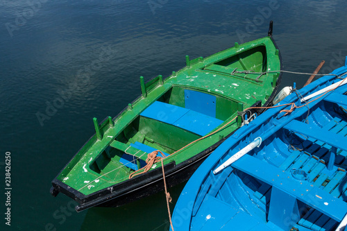Two blue and green boats anchored in a fishing port 