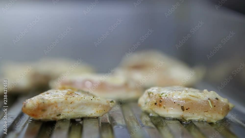 Pieces of chicken fillet are roasted on the electric plate. Side view. Pieces of chicken fillet are roasted on the electric plate. Side view.
