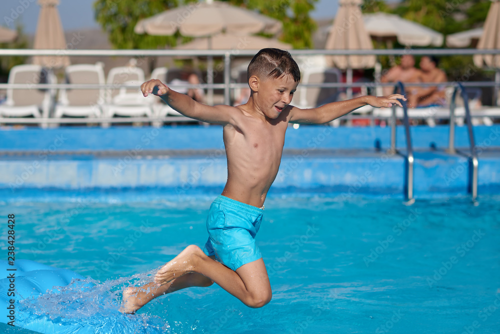 Smiling Caucasian boy having fun in swimming pool at resort on family vacation.