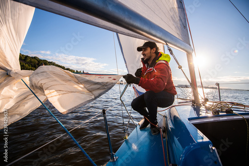 Beautiful inspiring shot of action adventure of sailor or captain on yacht or sailboat attaching big mainsail or spinnaker with ropes on deck of boat, sunny summer adventure lifestyle photo