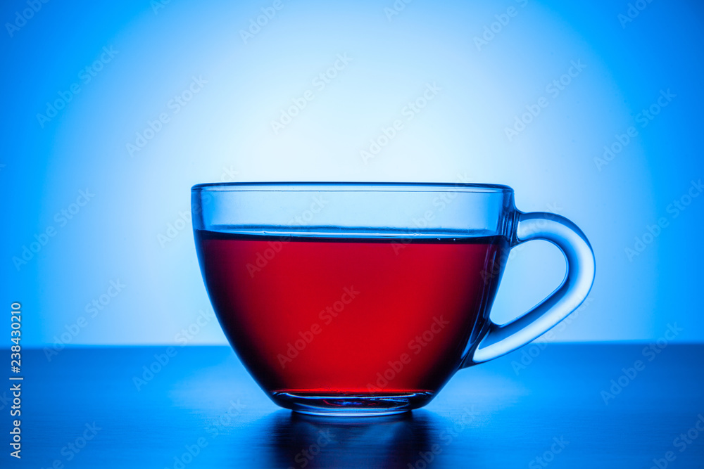 A transparent glass cup of tea stands on the table. A transparent glass cup of tea stands on the table.