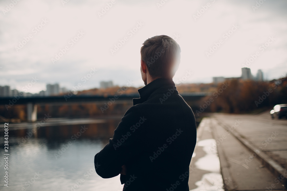 The man on the river embankment looks at the houses and the bridge in front of them. The man on the river embankment looks at the houses and the bridge in front of them.
