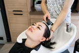Female client getting hair washed by hairstylist in parlor
